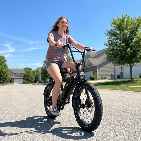 Jezdkyně na černém elektrickém kole DYU UX BMX v ulici obytné čtvrti